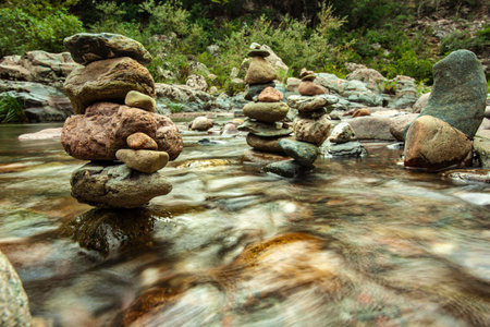 Stone cairns built in a river with flowing water in sa stiddiosa, sardinia, italy, creating a...