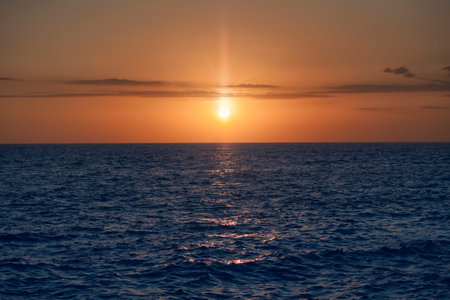 Golden hour sunlight casting a warm glow on the rippling ocean, creating a breathtaking reflection in the tranquil waters of the Dominican Republicの写真素材