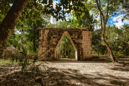 Stone archway stands amidst lush jungle vegetation at the Mayan ruins of Chichen Itza, Yucatan...