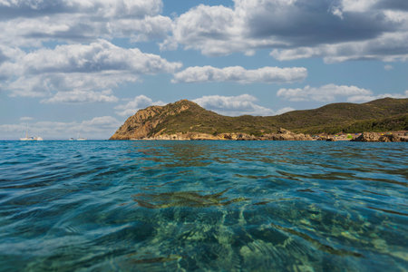 Calm, crystal clear water gently washing the sandy seabed of cala sa figu beach in sardinia, italy,...