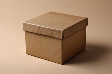 Closed textured light brown kraft cardboard box packaging resting on a beige background, creating a simple yet elegant compositionの素材