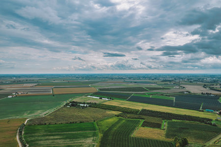 Geometric patterns of cultivated fields blanket the po valley landscape, showcasing a vibrant...