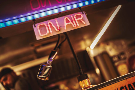 Glowing on air neon sign beside a vintage microphone in a cozy retro studio, evoking live radio or podcast recording, warm light, broadcast atmosphere, detailed close-upの写真素材