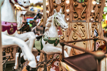 Detailed carousel horses featuring white and green accents with golden ornamental details, creating a feeling of childhood fun and nostalgic entertainmentの写真素材