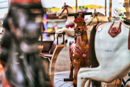 Carousel horses brightly painted and waiting on a classic amusement park merry-go-round, evoking childhood memories and providing entertainment at the fairの写真素材