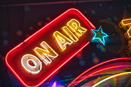 On air neon sign, with glowing red, yellow, and white letters, indicating a live broadcast or recording session, surrounded by other vibrant neon lights and a starの写真素材