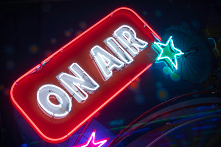Illuminated on air neon sign glowing red and blue against a dark urban backdrop, evoking live broadcasting, music, nightlife, streaming, studio vibes, and vibrant entertainment energyの写真素材