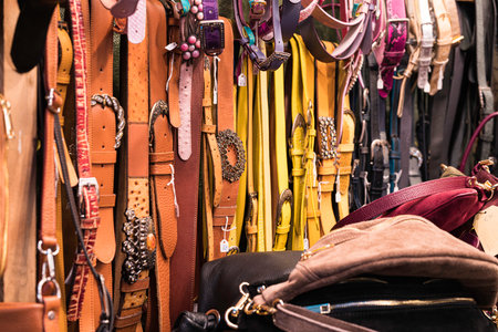 Retail store display featuring a collection of different leather belts with decorative buckles, alongside stylish handbags, offering variety for fashion accessoriesの写真素材