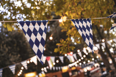 Bavarian rhombic flags and warm string lights decorating an outdoor event celebrating beer, tradition, and community, creating a festive German atmosphereの写真素材
