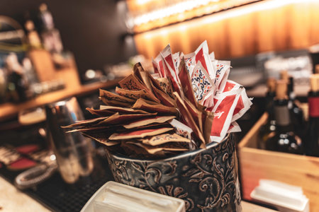 Rovigo, Italy 18 December 2025: ornate jar of sugar packets on warm-lit wooden bar counter, close-up evoking cozy cafe atmosphere and vintage hospitality ambianceのeditorial素材