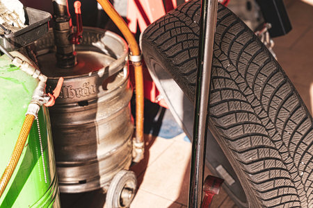 Rovigo, Italy 18 December 2025: auto service garage storage with winter tire, empty beer keg and green gas cylinder amid dusty, industrial workshop clutterのeditorial素材