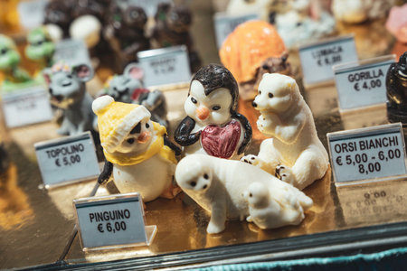 Rovigo, Italy 18 December 2025: cute marzipan and chocolate penguin, polar bear and seal figurines in a colorful confectionery window display for saleのeditorial素材