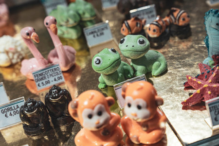 Rovigo, Italy 18 December 2025: colorful marzipan frogs, monkeys, and flamingos on golden display, ready for sale as souvenirs in an Italian candy shopのeditorial素材