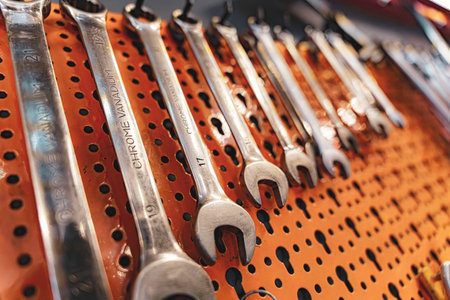Rovigo, Italy 18 December 2025: chrome vanadium spanners neatly hanging on a bright orange pegboard, organized and ready for professional repair and maintenance tasksのeditorial素材