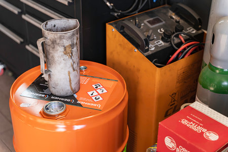 Rovigo, Italy 18 December 2025: workshop corner with tools, an oil barrel, and vehicle battery charger. Indicating repairs, maintenance, and automotive industry workのeditorial素材
