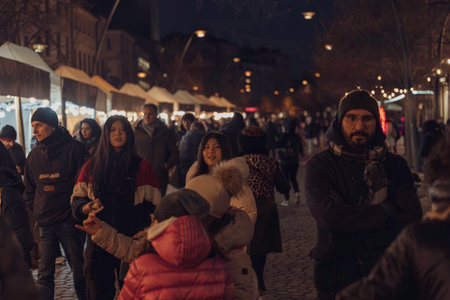 Rovigo, Italy 18 December 2025: people walking among stalls and string lights at urban street market, celebrating seasonal gathering during a cold eveningのeditorial素材