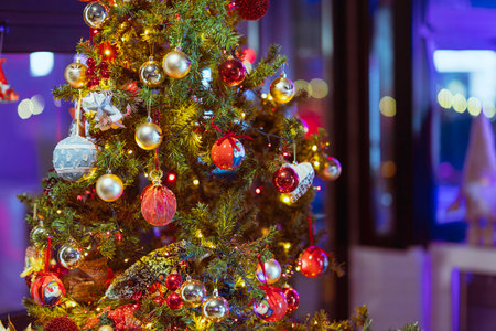 Rovigo, Italy 18 December 2025: christmas tree branches adorned with glowing lights and colorful baubles, creating a warm, festive holiday atmosphereのeditorial素材