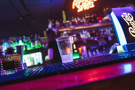 Rovigo, Italy 18 December 2025: empty plastic cup on a neon-lit bar counter, moody nightclub...