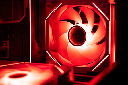 Red rgb computer case fan glowing inside a gaming desktop, casting neon light over motherboard and cpu cooler while efficiently cooling high-performance hardware componentsの写真素材