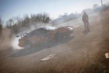 Imola, italy 01 january 2026: orange sport car performing a drift, generating a lot of smoke on an...