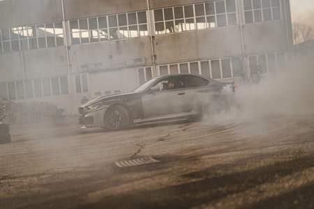 Imola, italy 01 january 2026: grey sports car executing a controlled drift on asphalt, tires smoking...