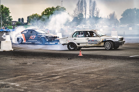 Milan, italy 21 april 2026: two bmws tandem drifting on asphalt track, tires smoking as drivers push speed and control in intense motorsport action