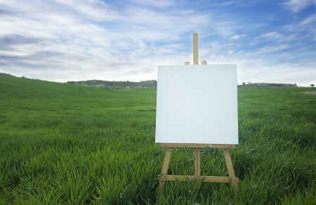 Blank canvas on a wooden easel over a field の写真素材