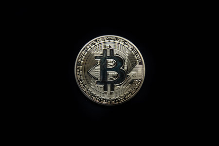 Physical gold Bitcoin isolated against a black background