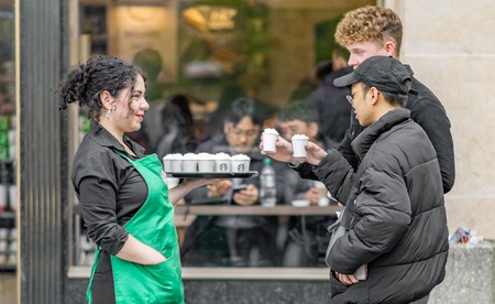 PRAGUE, CZECHIA - 12TH APRIL 2019: A female Starbucks employee hands out warm samples to the Public in Prague old town squareのeditorial素材