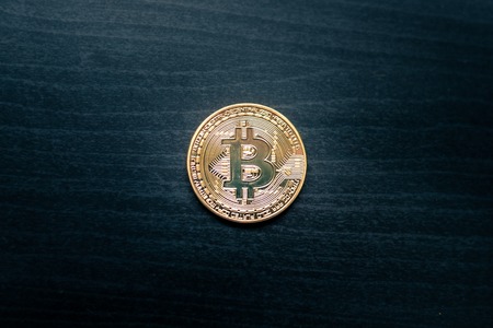 A physical bitcoin in the middle of a dark wooden backgroundの写真素材
