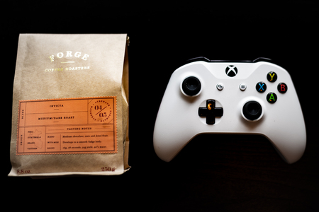 Xbox One games controller sat next to a bag of ground coffee against a dark black backgroundのeditorial素材