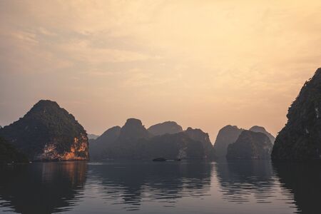 Ha Long Bay in Vietnam during a beautiful Sunset with calm, tranquil seas. Shot in Autumn 2019 from a cruise ship tourの写真素材