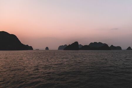 Ha Long Bay in Vietnam during a beautiful Sunset with calm, tranquil seas. Shot in Autumn 2019 from a cruise ship tourの写真素材