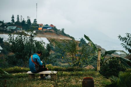 A local Vietnamese woman makes clothes surrounded by rice terraces in the small mountain town Sapa in the Northern mountains of Indochinaの写真素材