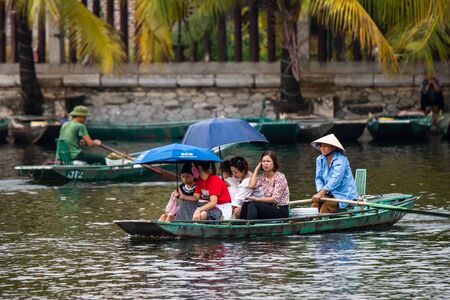 Tam Coc, Vietnam, 16th October 2019: Vietnamese locals row rowing boats with their feet for tourists as they travel on a boat tour through the limestone caves of Ninh Binhのeditorial素材
