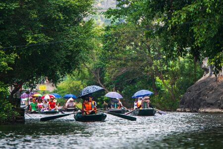 Tam Coc, Vietnam, 16th October 2019: Asian tourists travel on a rowing boat tour through the limestone caves of Ninh Binh on a sunny dayのeditorial素材