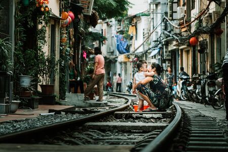 Hanoi, Vietnam - 18th October 2019: A mother bathes her son in public using a tub on railway tracks at the famous Train Street in Hanoi, Vietnamのeditorial素材