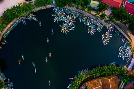 Aerial footage of crowds of people taking boat tours through Tam Coc and Ninh Binh travelling underneath limestone cavesの写真素材