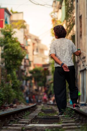 Hanoi, Vietnam - 18th October 2019: A local woman living on the world famous Train Street in Hanoi, Vietnam waters the plants and her garden as tourists walk byの写真素材