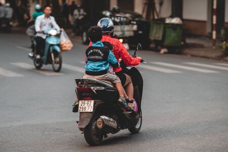 Hanoi, Vietnam - 18th October 2019: Parents take their children to school on a moped in the busy streets of Hanoi without any protection or a helmetのeditorial素材