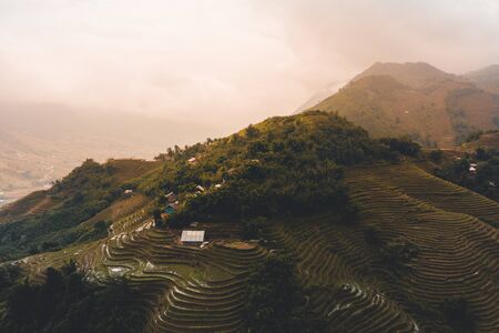 Beautiful Aerial shot of sunrise over the rice terraces of Sapa in North Vietnam during Autumn as the clouds pass over the peaks of the mountainsの写真素材