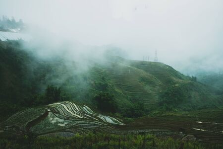 Flooded rice terraces reflecting light at dusk around sunset in Sapa, North Vietnam, high up in the mountains as the clouds clear around the peaksの写真素材