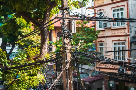 Messy tangled wires around a power pole in Hanoi, Vietnam. Close up shot showing the mess and disorder that the wires poseの写真素材
