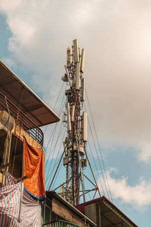 Communication Antenna Mast stucture built on top of building in Vietnam, Asia with clouds in the background during sunsetの写真素材