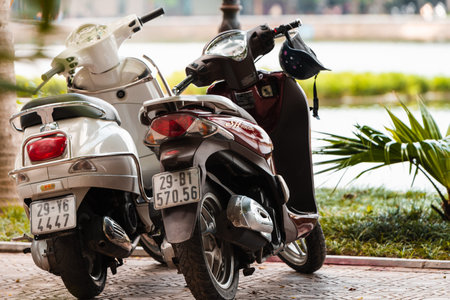 Hanoi, Vietnam - 11th October 2019: Two scooters stand in a line in Hanoi in front of a large lake...