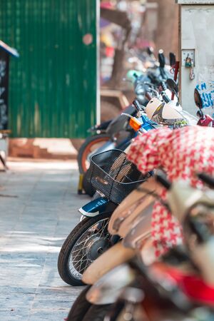 Rows of colorful scooters, mopeds and bikes parked in a row on a quiet street in Hanoi, Vietnam, Asiaの写真素材