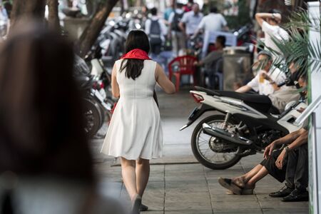 An asian woman wearing a bright red scarf that was bought as a present walking through the streets of Hanoi, Vietnam, Asiaの写真素材
