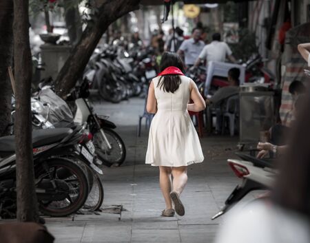 An asian woman wearing a bright red scarf that was bought as a present walking through the streets of Hanoi, Vietnam, Asiaの写真素材