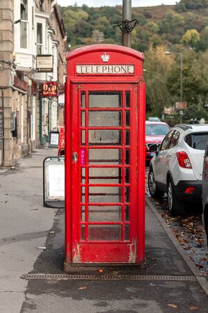 Matlock, UK - 6th October 2018: An old bright British iconic red telephone box in the middle of the frame in an English townのeditorial素材