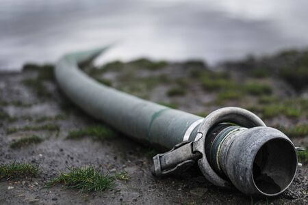 Close up dramatic moody shot of waste pipe that goes into a river on a cloudy dayの写真素材